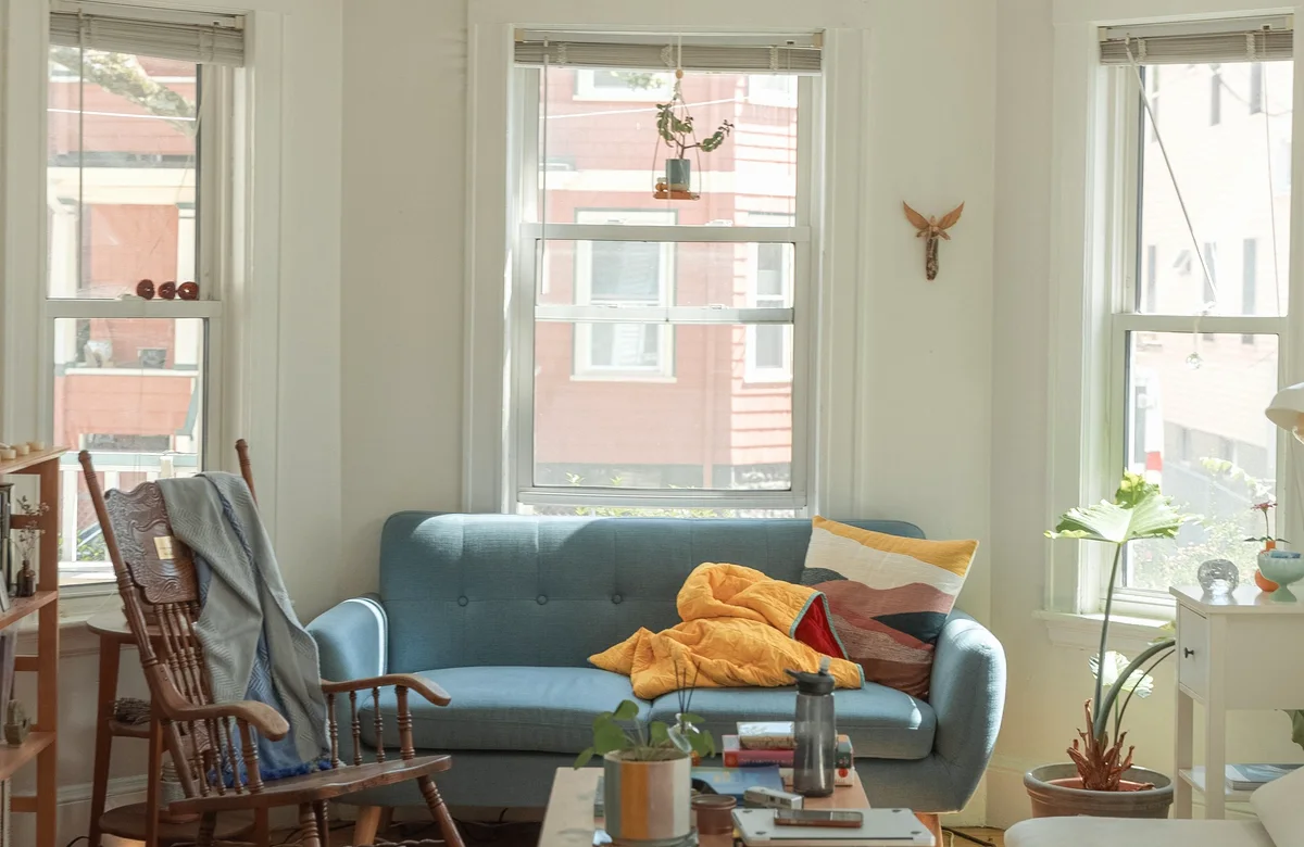 Heller Wohnraum mit blauem Sofa und großen Fenstern